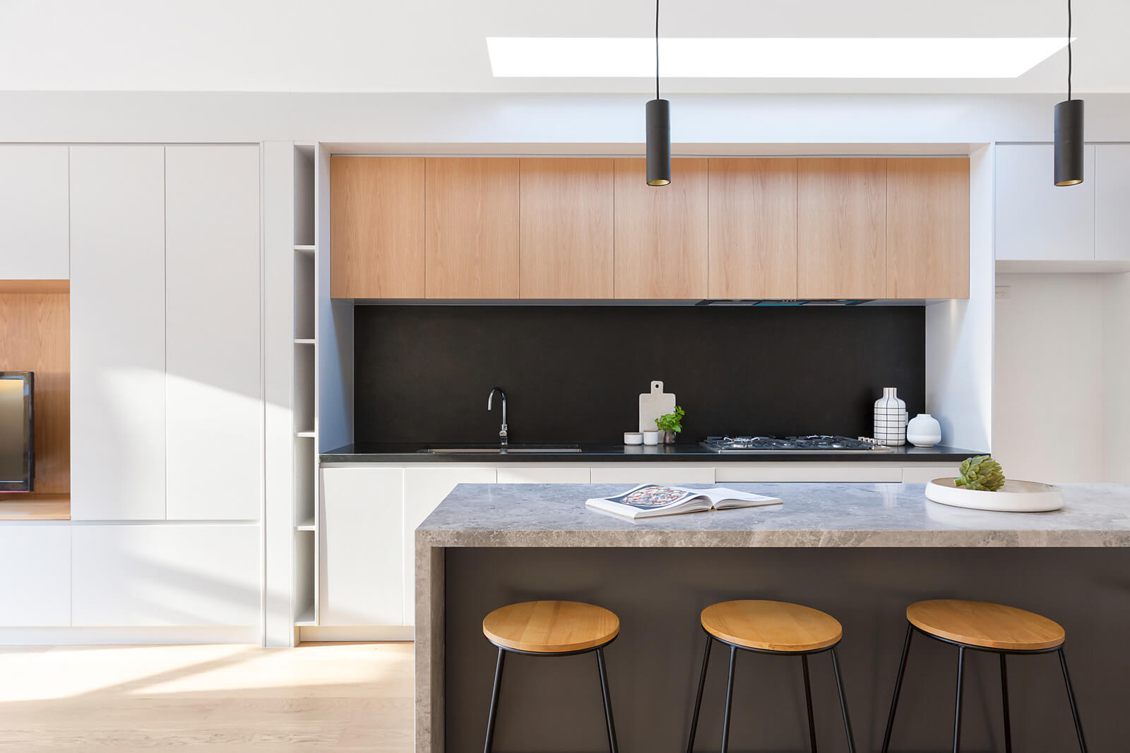 Modern kitchen with black splash back and timber top bar stools