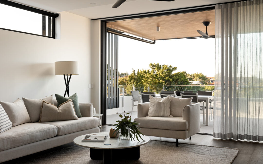 Living room opening to balcony in Clayfield home. With lounge suite styled with square cushions.